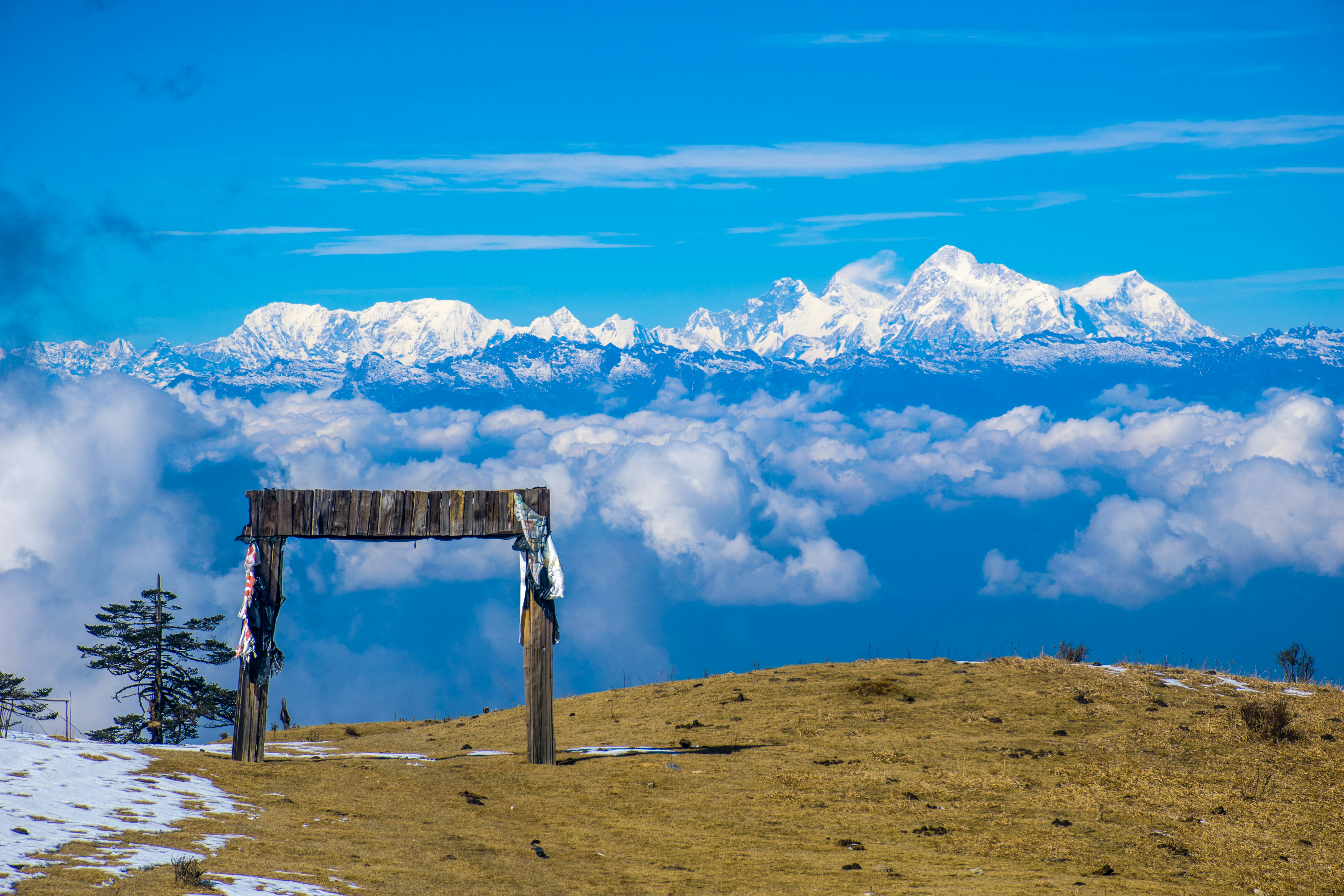 brown wooden bench on brown field under blue and white cloudy sky during daytime sandakphu